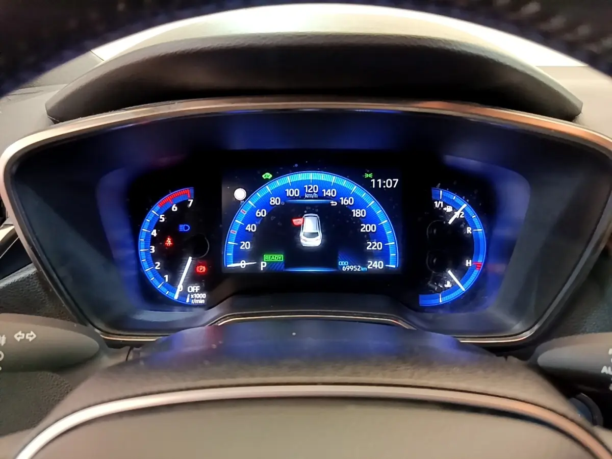 Tableau de bord numérique de Toyota Corolla Hybride 2022, affichage bleu avec compteur vitesse et indicateurs variés.