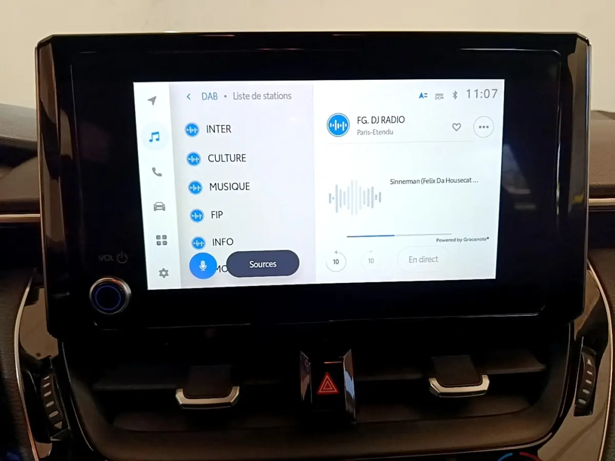 Écran tactile central 8 pouces affichant la radio numérique dans l’habitacle d’une Toyota Corolla blanche.