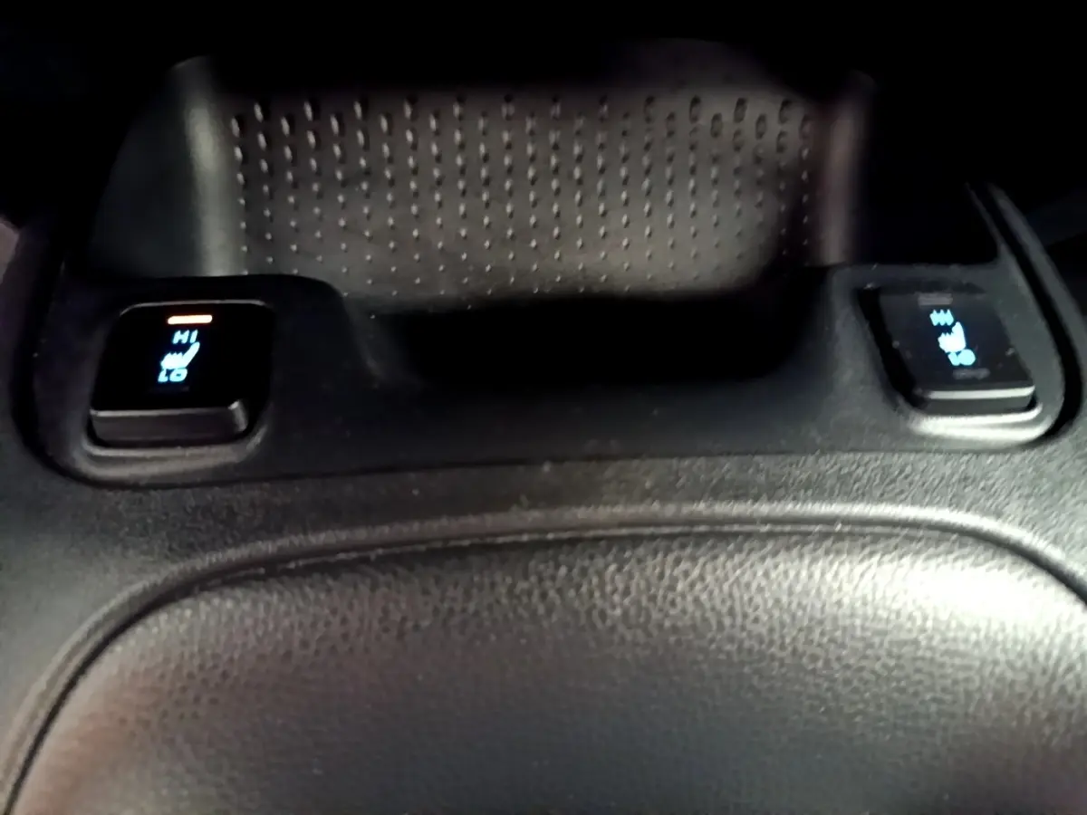 Détail des commandes de chauffage des sièges arrière sur la console centrale en cuir noir de la Toyota Corolla hybride blanche.