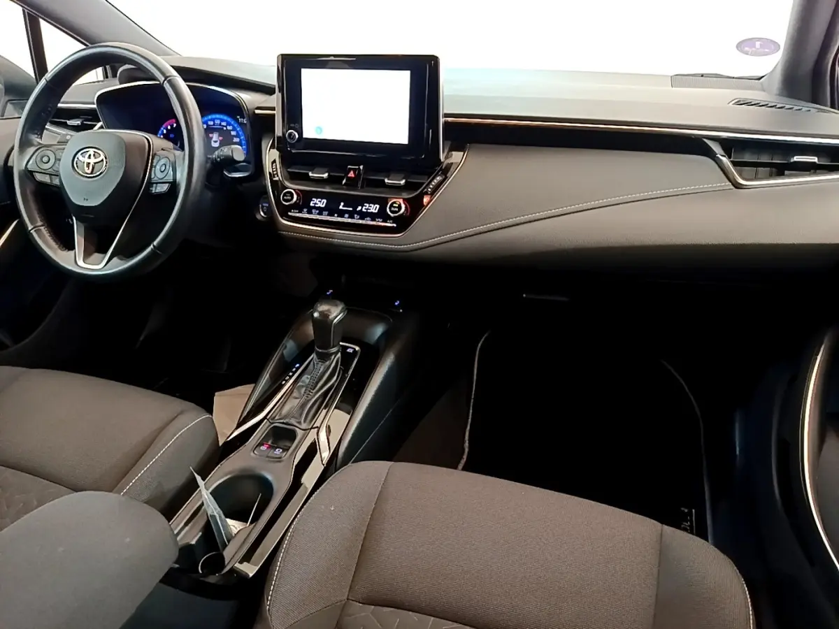Intérieur de la Toyota Corolla Hybride 2022 vu de face, avec tableau de bord noir et écran tactile central.