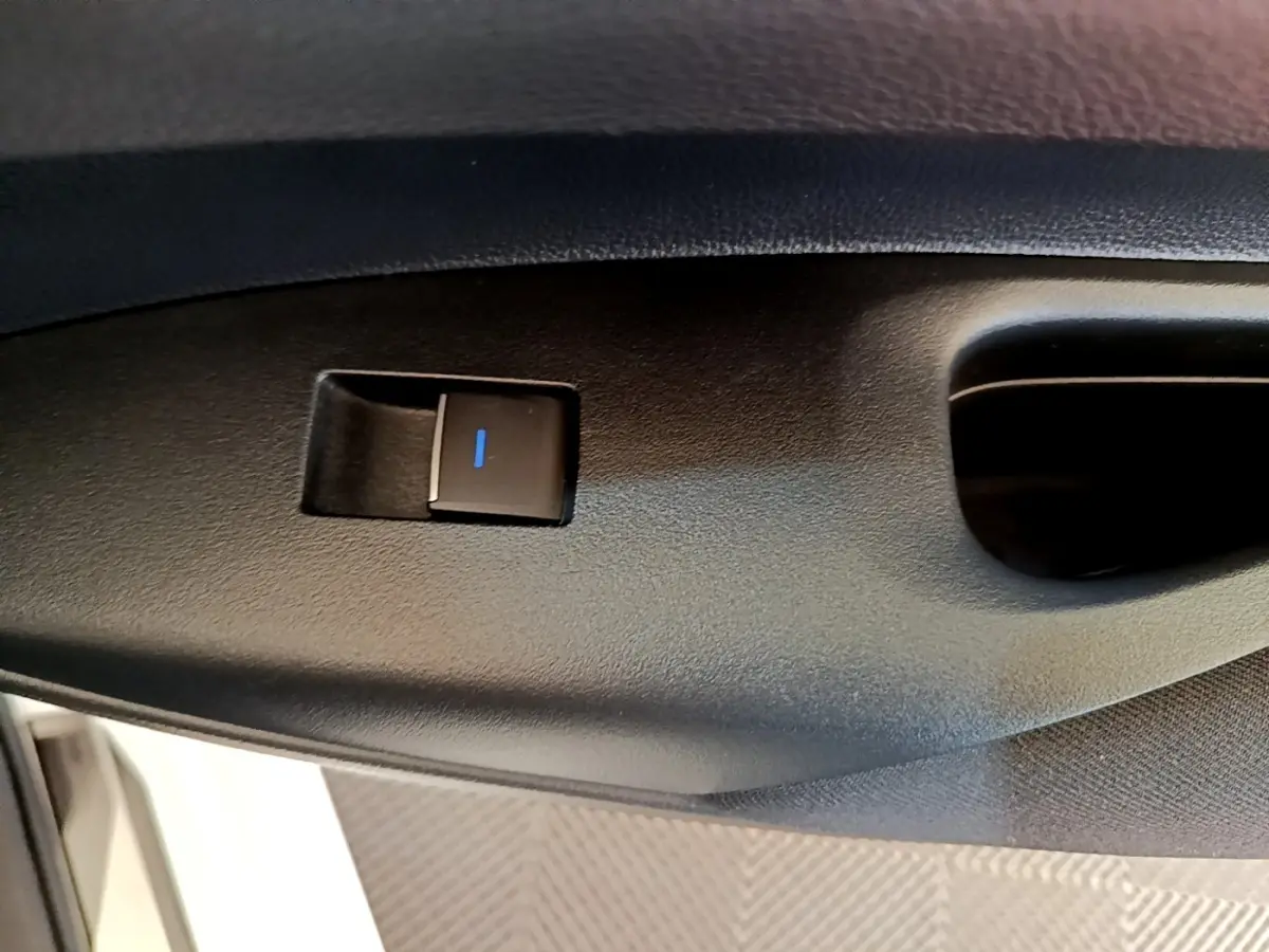 Détail du bouton de verrouillage électrique sur la porte intérieure côté conducteur de la Toyota Corolla blanche hybride 2022.