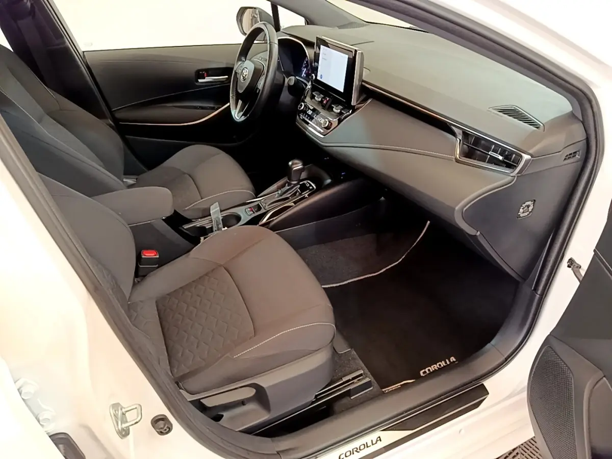 Vue intérieure côté conducteur de la Toyota Corolla blanche 2022, avec tableau de bord moderne et écran tactile central.