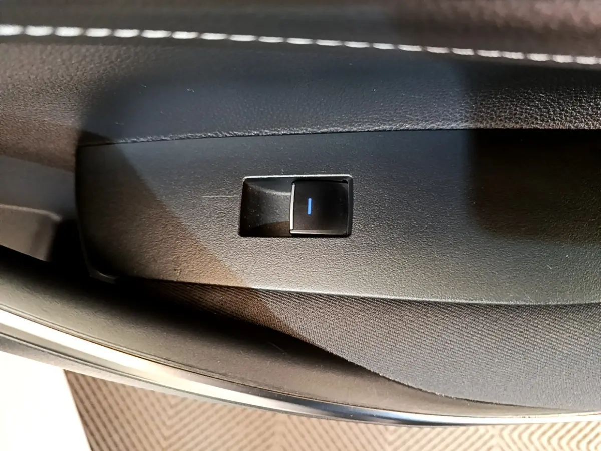 Gros plan sur l'interrupteur de verrouillage des portes côté conducteur d'une Toyota Corolla hybride blanche 2022.