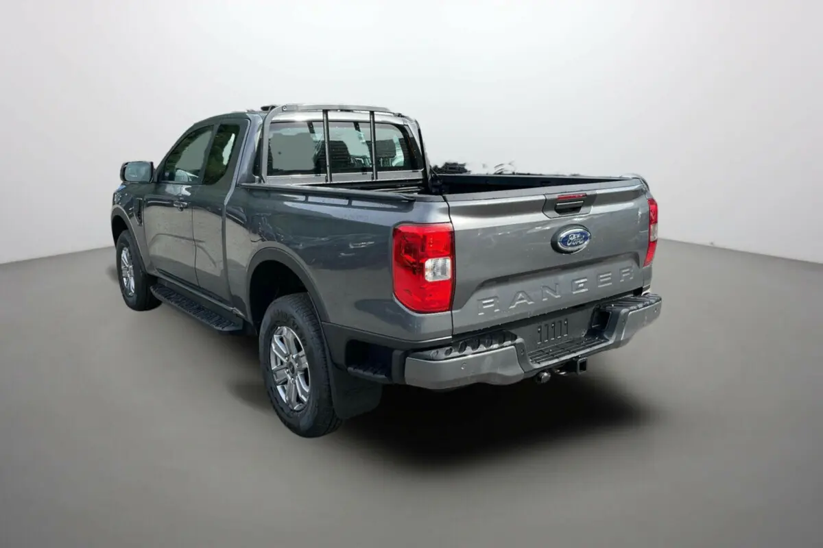 Ford Ranger gris carbone en 3/4 arrière droit, mettant en valeur la benne ouverte et l'attelage robuste.