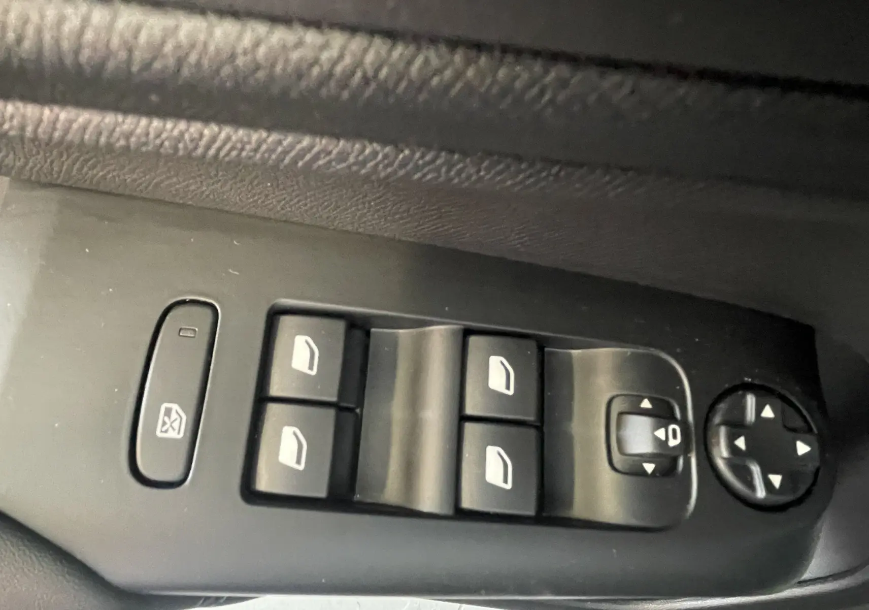 Vue rapprochée des commandes de lève-vitres et réglage des rétroviseurs sur la porte côté gauche du Citroën C5 Aircross gris platinium.