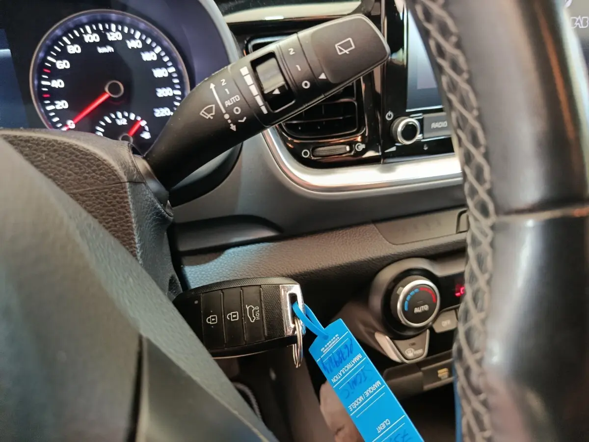 Gros plan sur le volant et tableau de bord du Kia Stonic gris foncé, avec clé de contact et commandes visibles.
