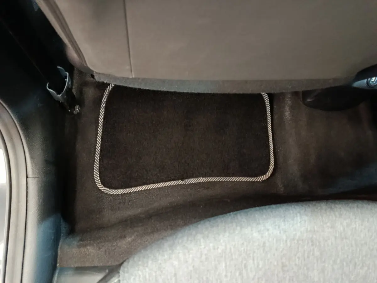 Vue rapprochée du tapis de sol arrière noir avec bordure claire dans une KIA Stonic gris foncé 2023.