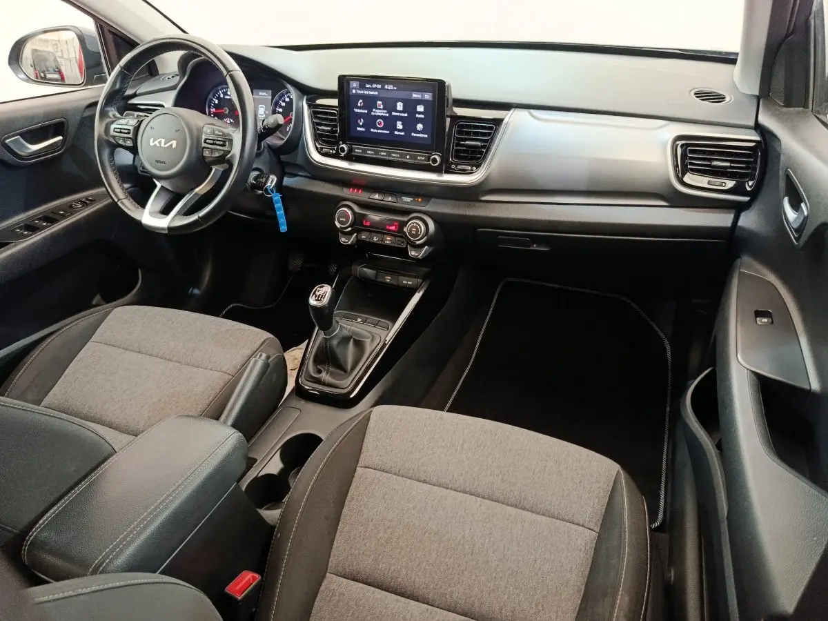 Vue intérieure côté conducteur de la Kia Stonic 2023, tableau de bord avec écran tactile et volant cuir multifonctions.