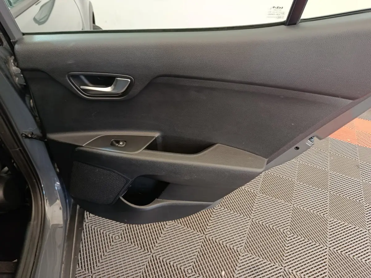 Vue intérieure de la porte arrière gauche du KIA STONIC gris foncé, avec poignée et commande de vitre électrique.