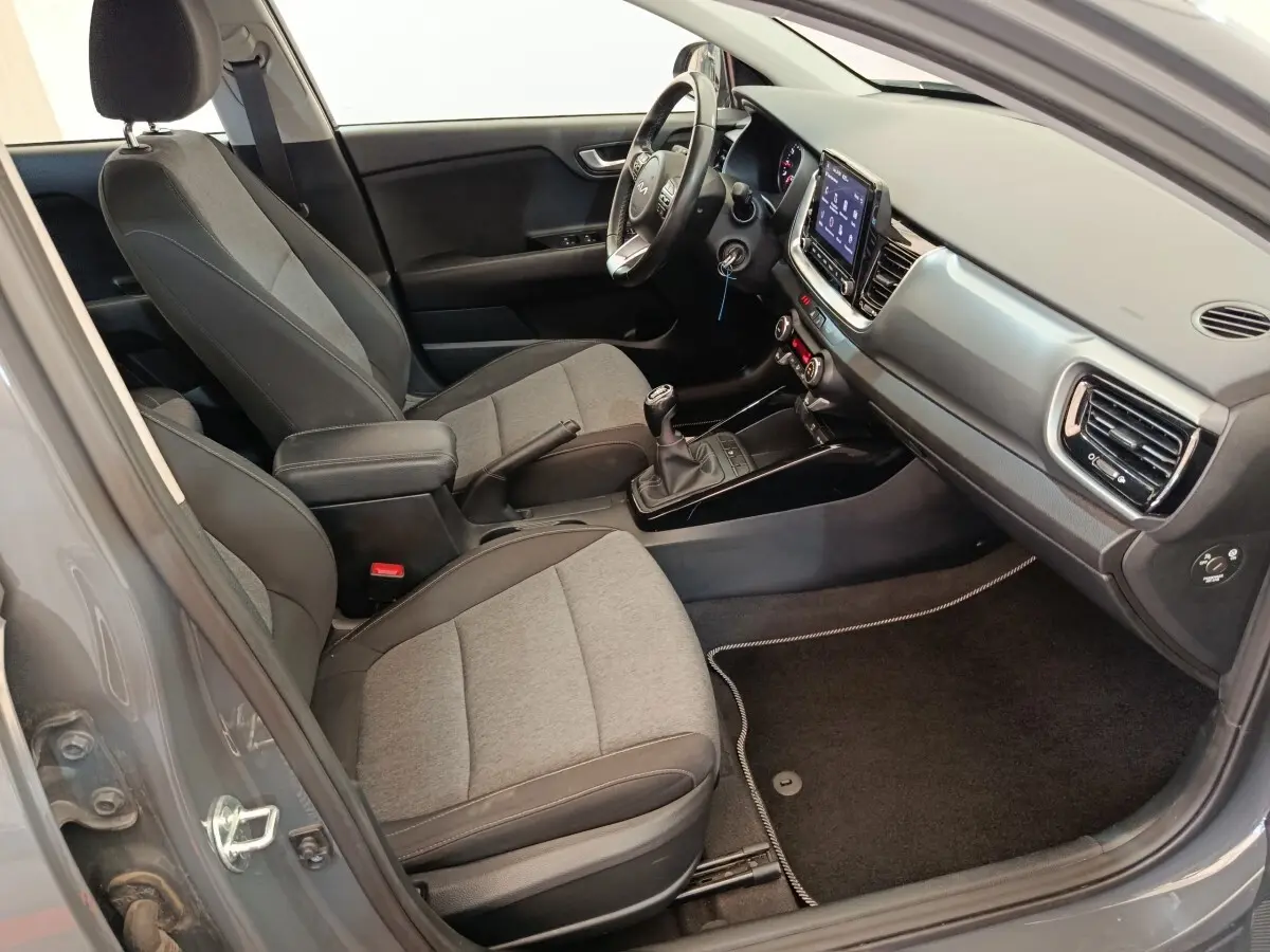 Vue intérieure côté conducteur de la KIA Stonic gris foncé 2023, avec tableau de bord moderne et écran tactile central.