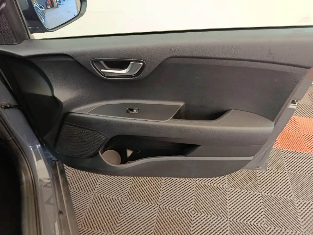 Vue intérieure de la porte avant gauche gris foncé du KIA STONIC 2023 avec poignée et commande de fenêtre simple.