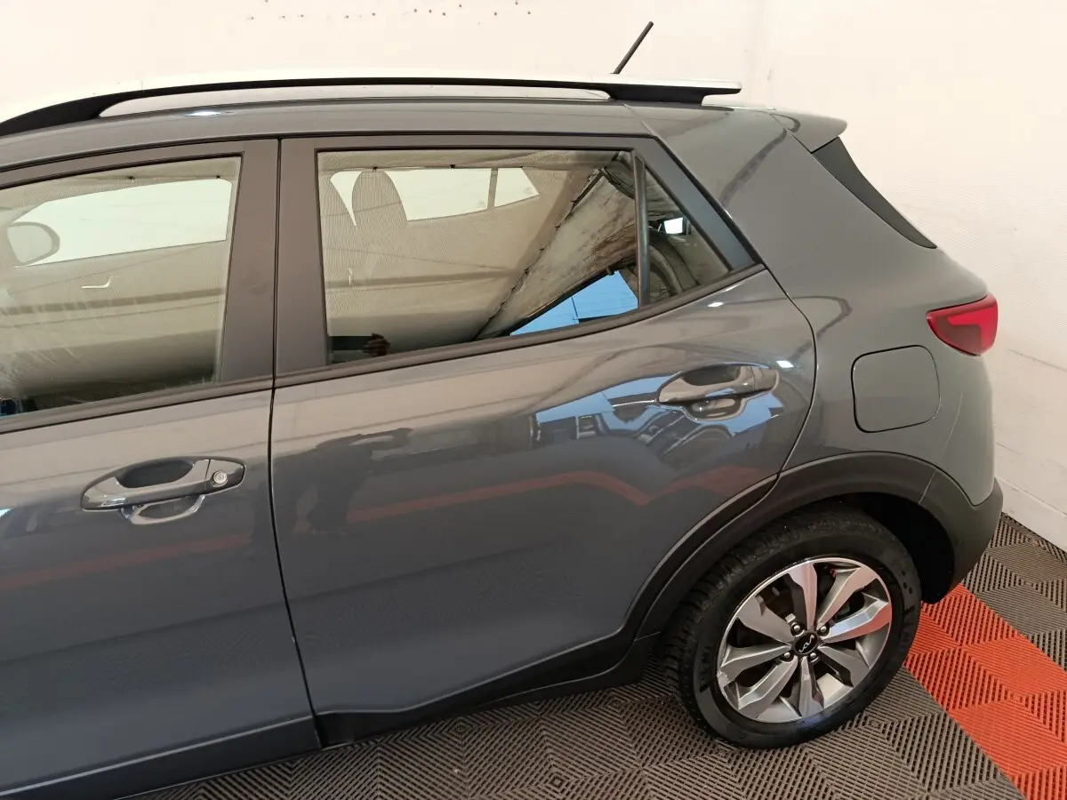 Vue latérale droite d'un KIA Stonic gris foncé montrant la porte arrière, la roue et la lunette arrière.
