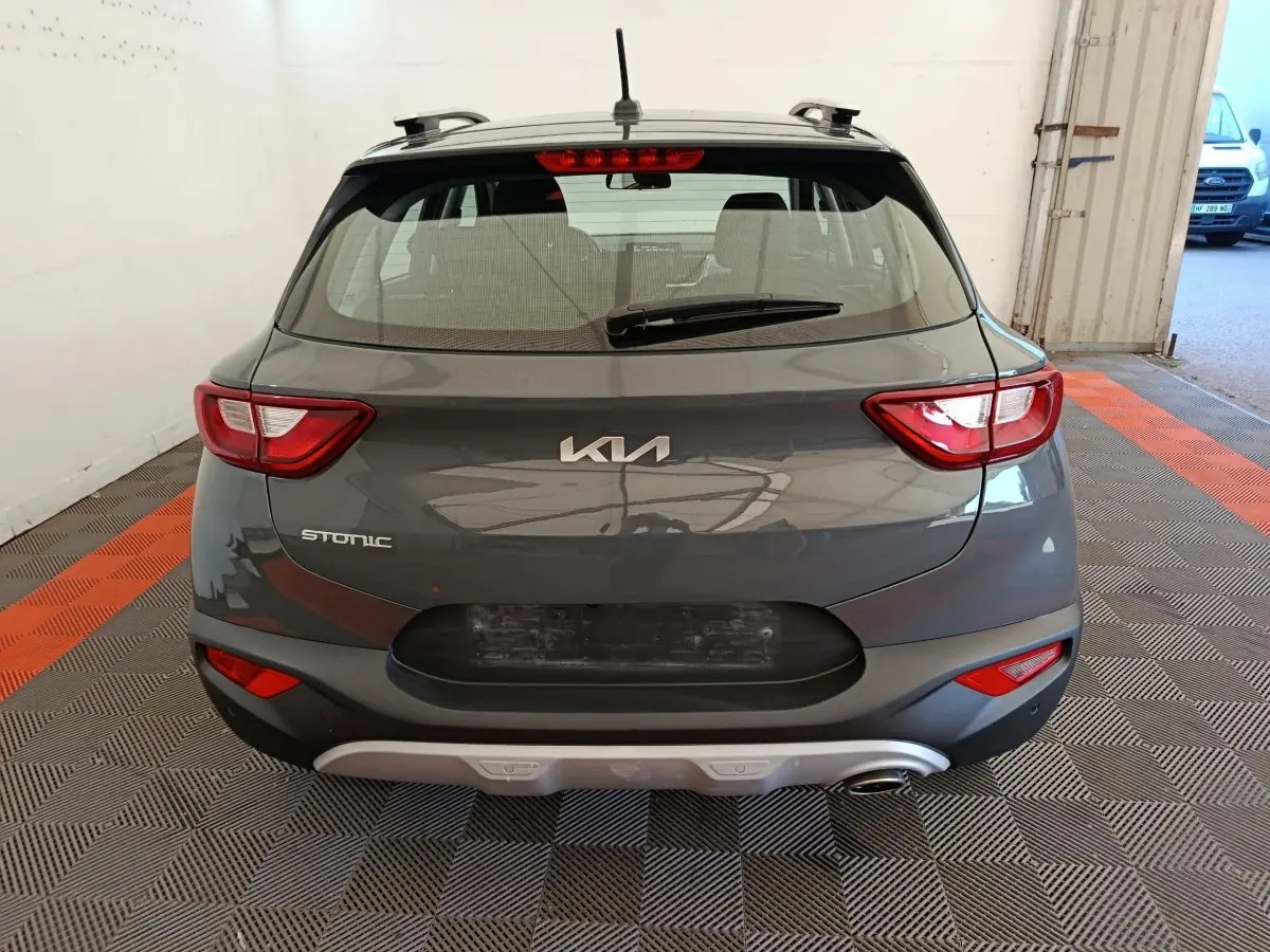 Vue arrière d'un KIA Stonic gris foncé 2023, mettant en valeur ses feux arrière distinctifs et son logo central.