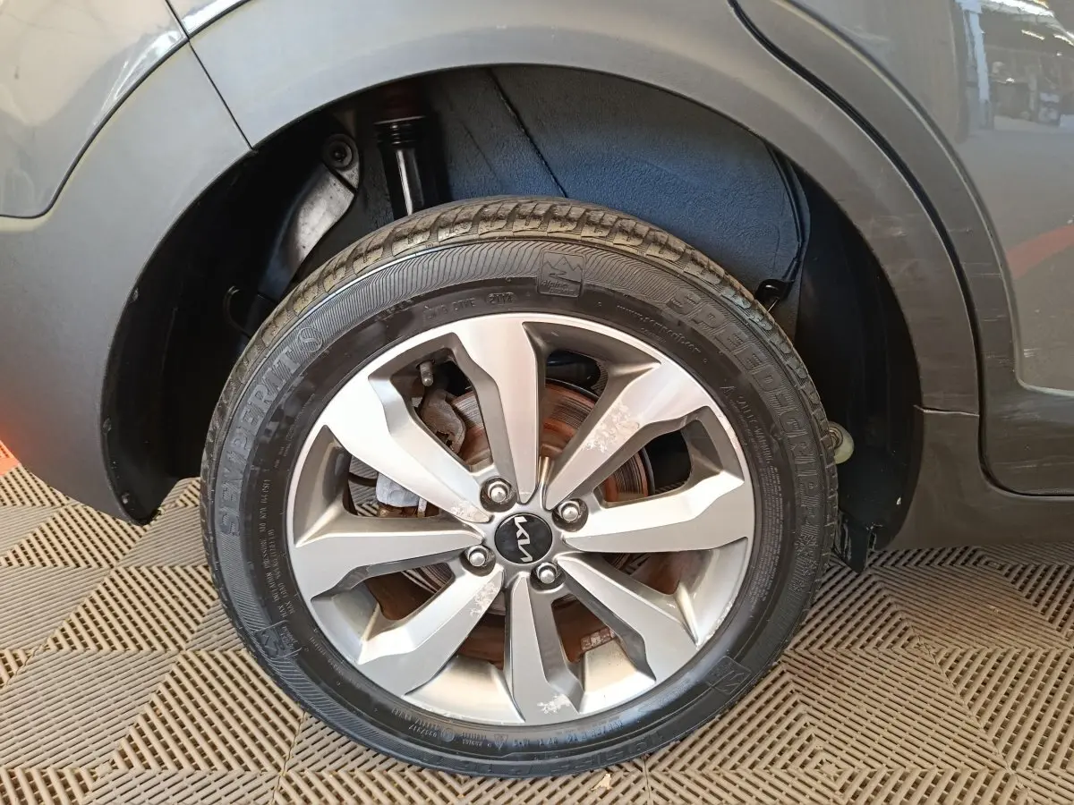 Gros plan sur la roue avant droite d’un KIA Stonic gris foncé, mettant en valeur la jante alliage et le logo central.
