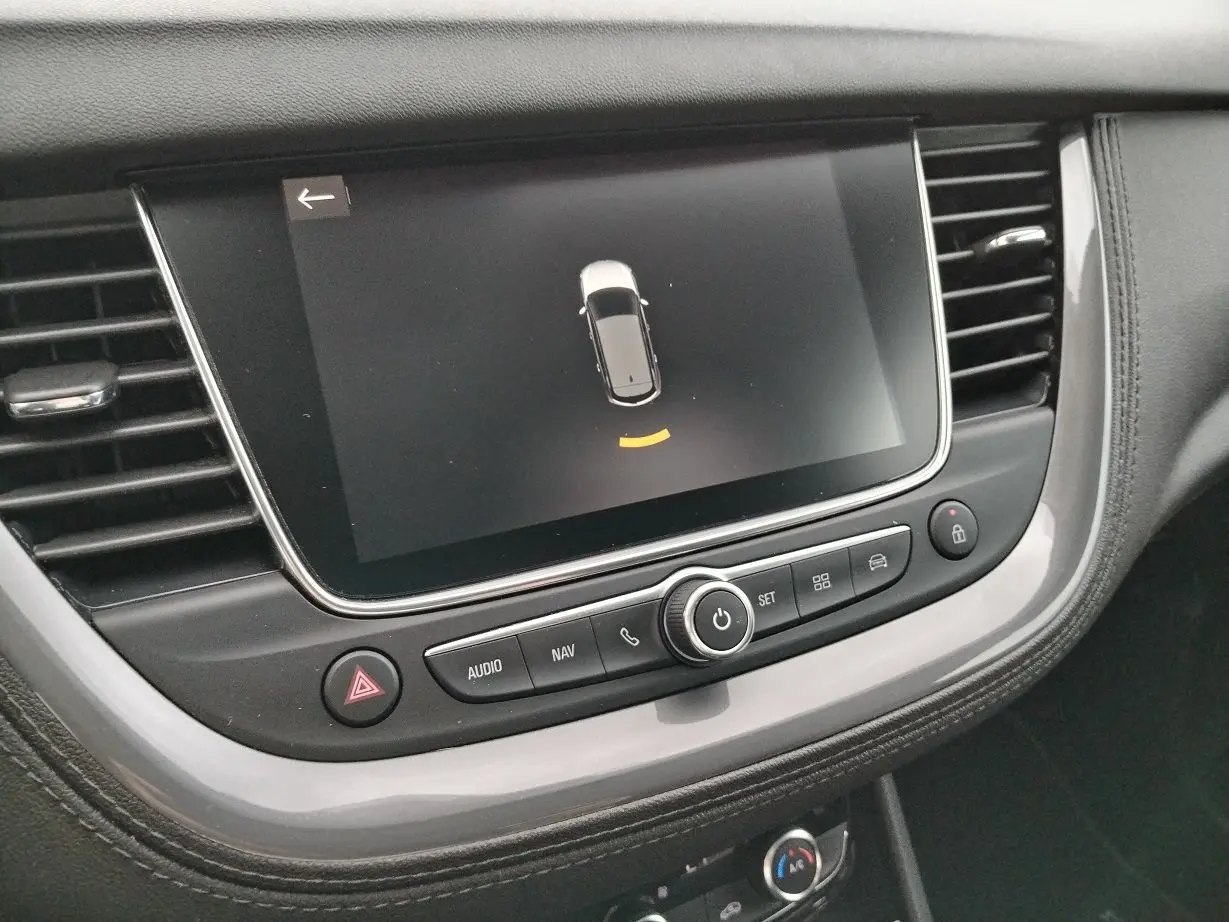 Écran tactile central de l'Opel Grandland X 2019 affichant l'aide au stationnement, entouré de commandes audio et navigation.