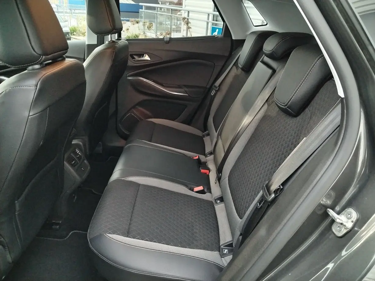 Vue intérieure arrière côté droit de l'Opel Grandland X gris platinium, mettant en valeur les sièges en tissu et cuir noir avec surpiqûres grises.