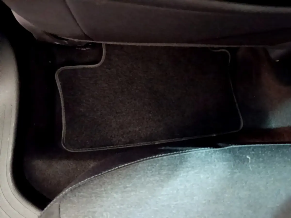 Vue rapprochée du tapis de sol noir côté passager arrière d'une Renault Clio Business Blue dCi 85 blanche de 2020.