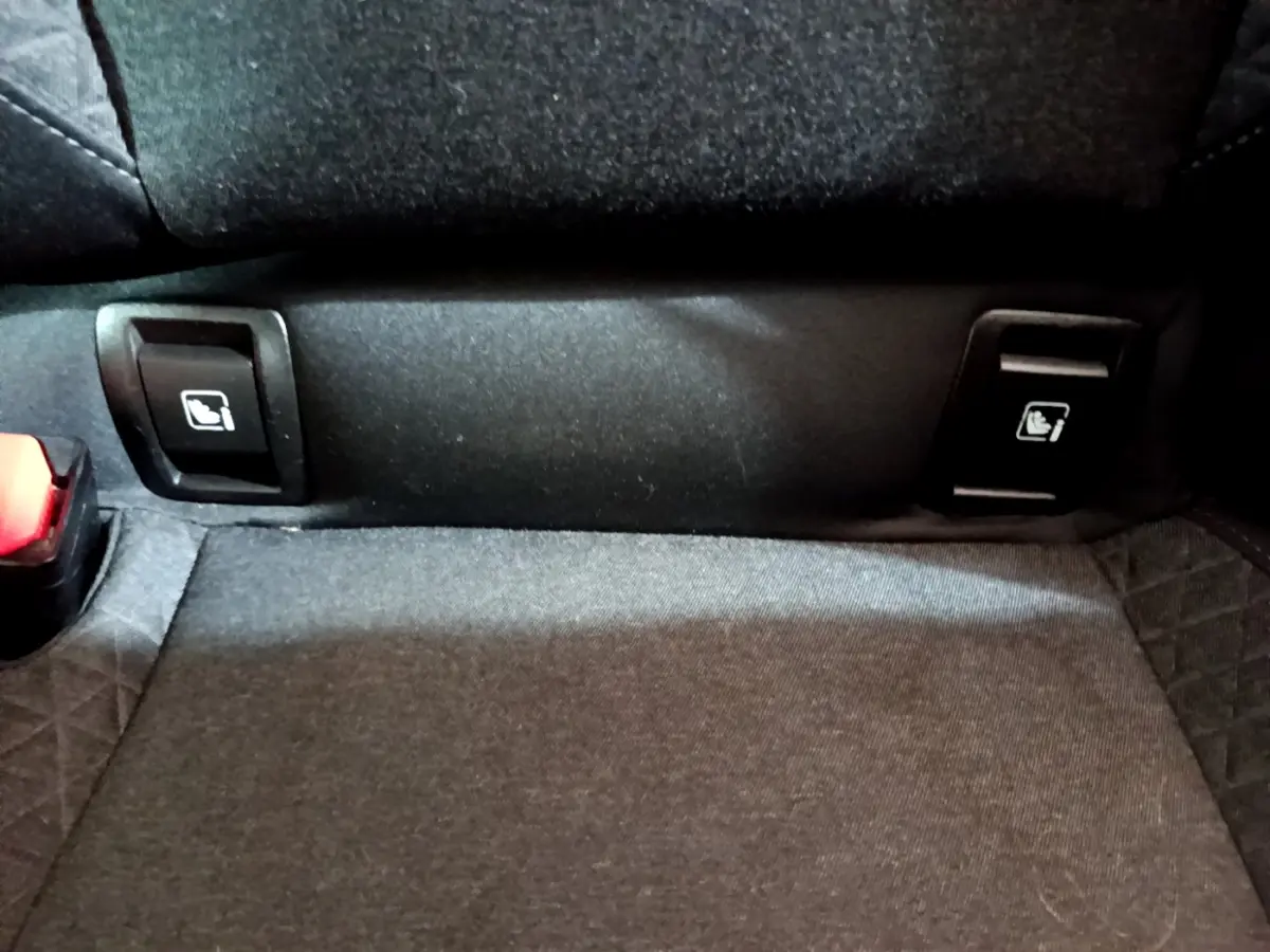 Détail des commandes de rabattement des sièges arrière noirs dans une Renault Clio Business Blue dCi 85 blanche de 2020.