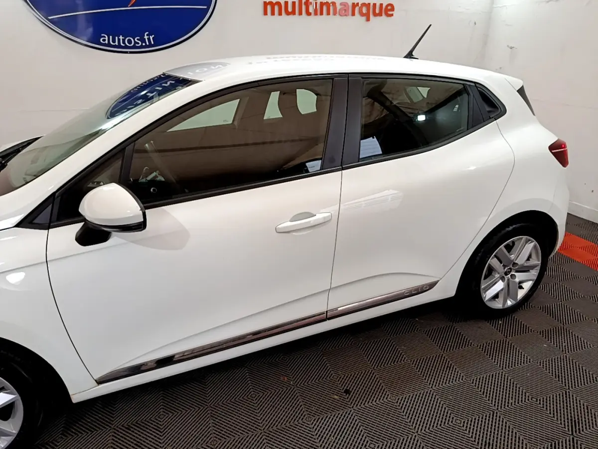 Profil côté gauche d'une Renault Clio blanche Business Blue dCi 85, avec jantes alliage et poignées de porte intégrées.