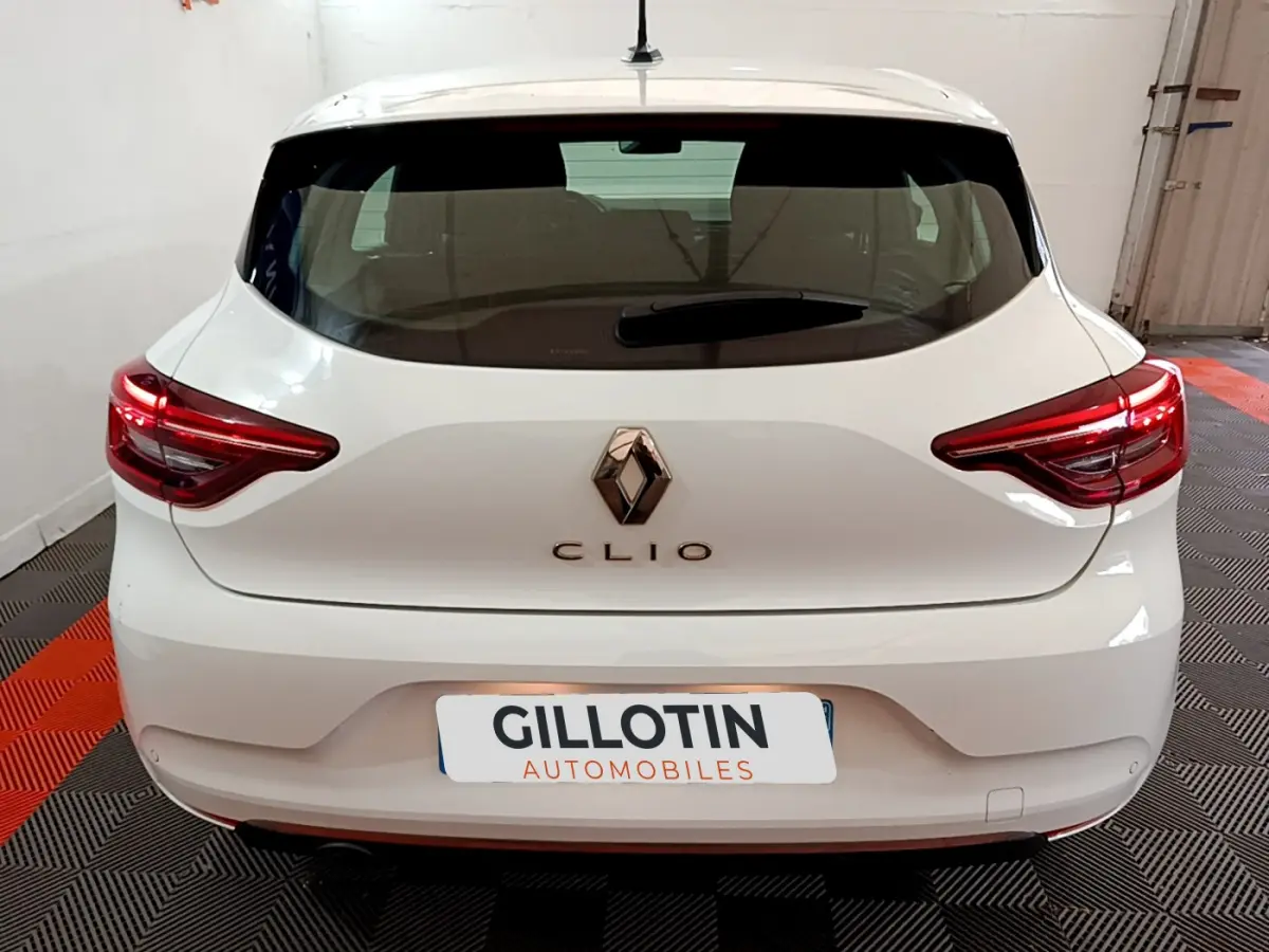 Vue arrière d'une Renault Clio blanche 2020 avec feux LED et logo Renault bien visibles dans un garage.