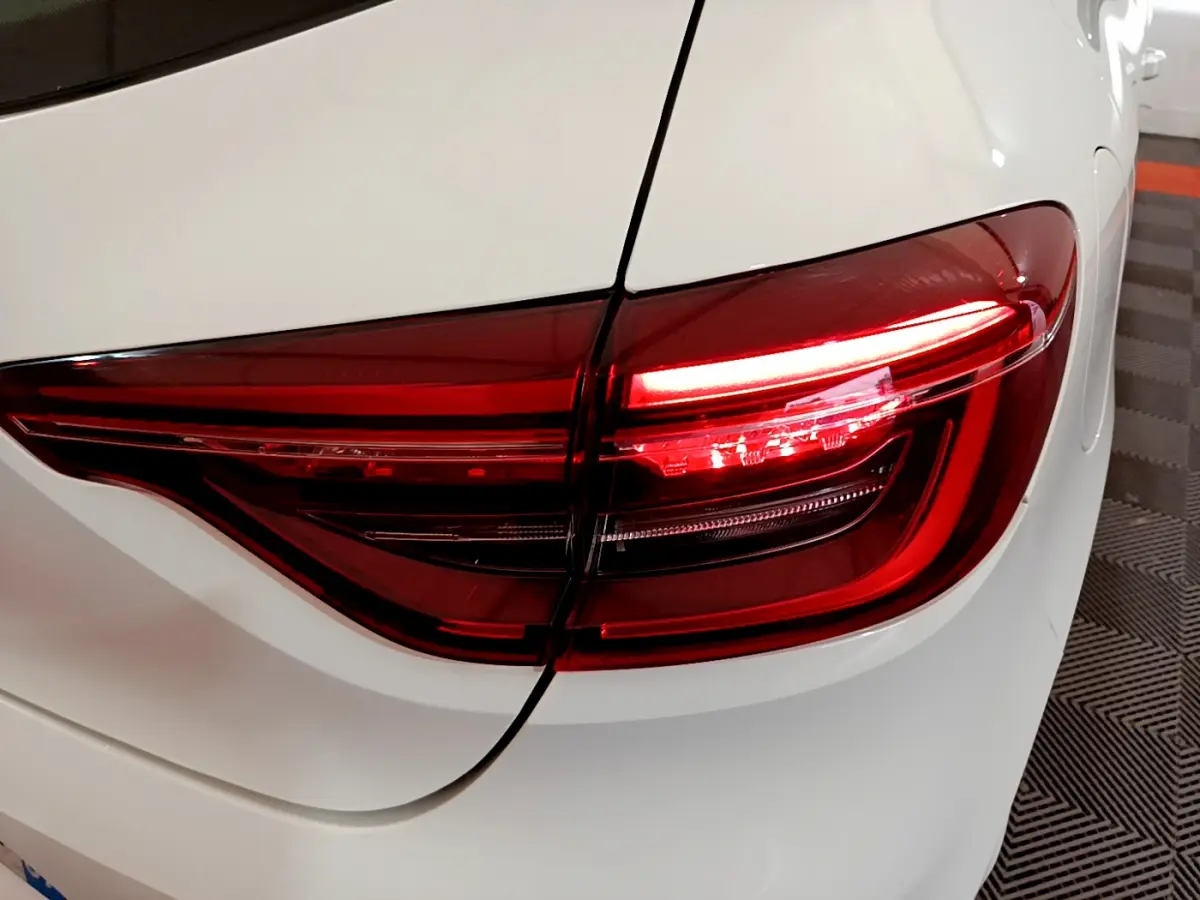 Gros plan sur le feu arrière droit rouge d'une Renault Clio Business Blue dCi 85 blanche, vue arrière détaillée.