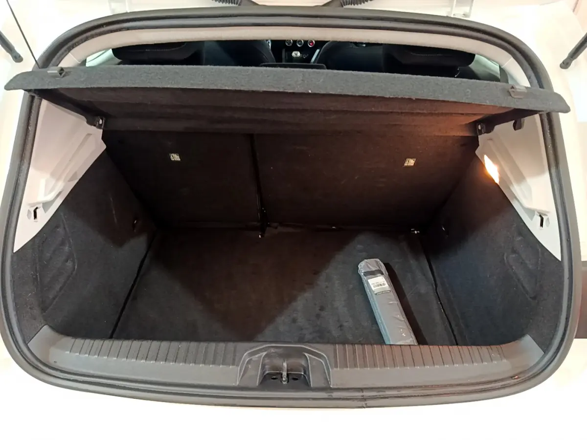 Coffre ouvert vu de l'arrière d'une Renault Clio Business Blue dCi 85 blanche, intérieur noir avec un objet emballé.