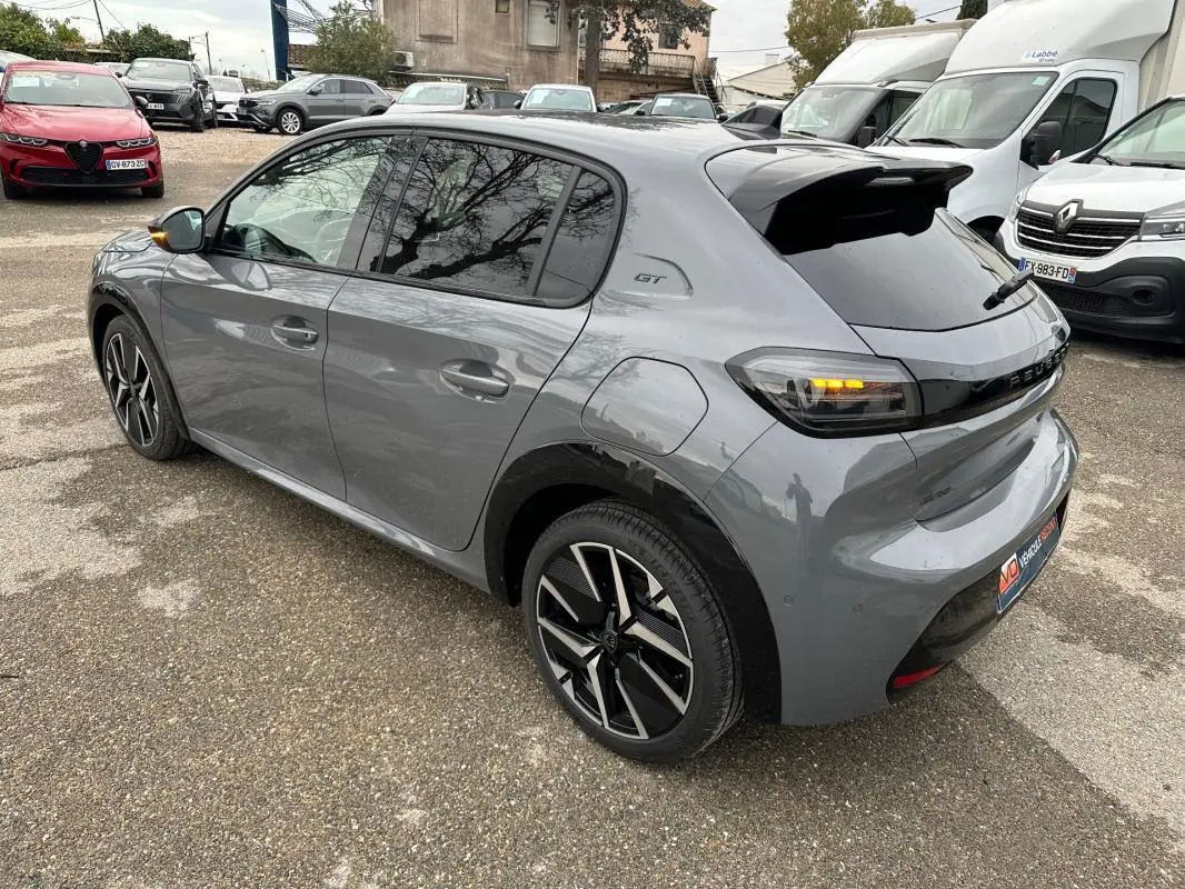 Vue 3/4 arrière droite d’une Peugeot 208 Hybrid 110 gris métallisé avec jantes alliage 17 pouces et feux arrière allumés.
