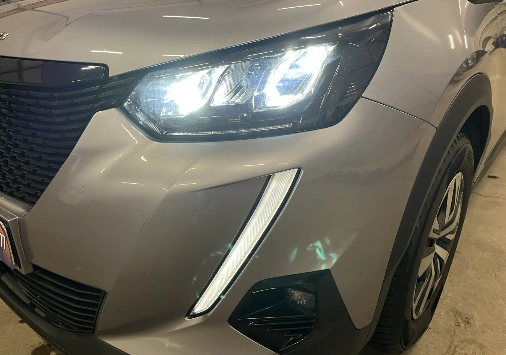 Gros plan sur l'avant droit gris alu du Peugeot 2008 Active Business 2020, avec phares LED allumés et jante visible.