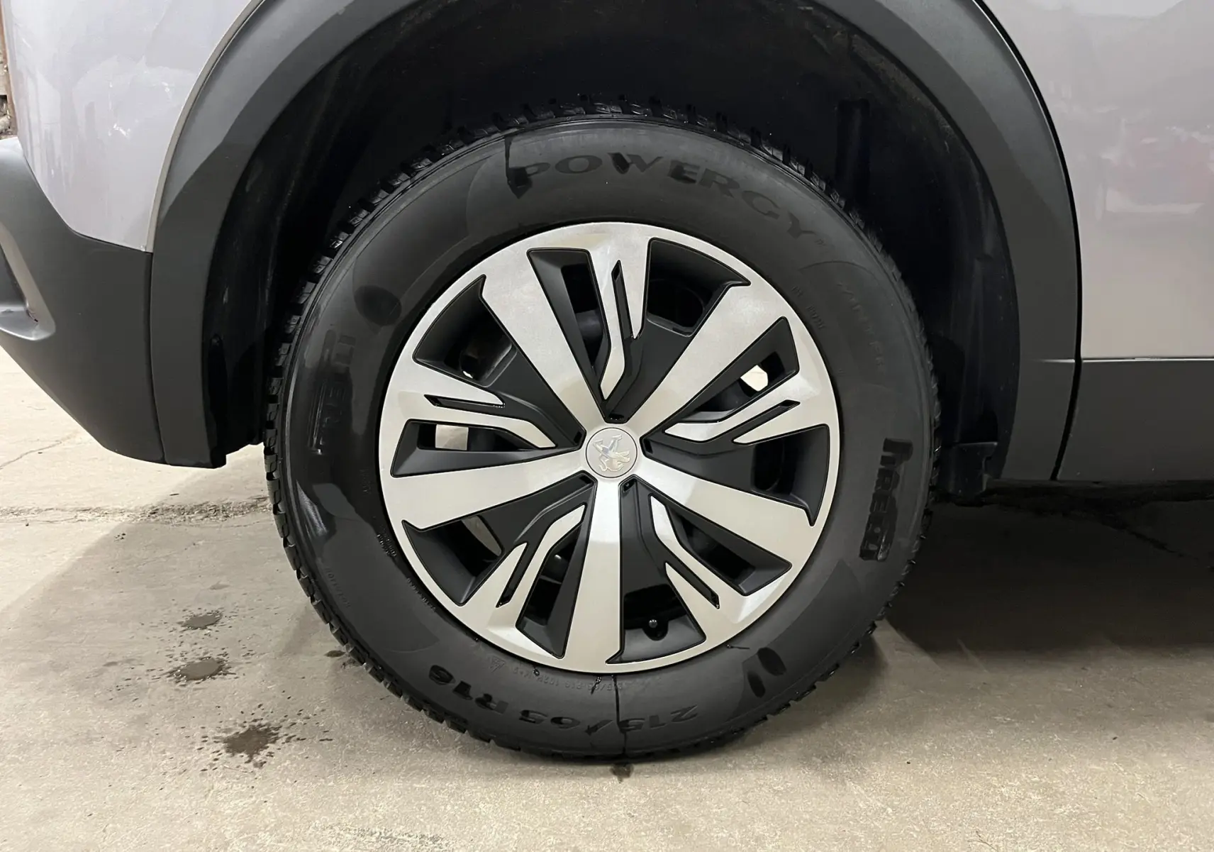 Gros plan sur la roue avant gauche du Peugeot 2008 gris alu, mettant en valeur la jante alliage au design moderne.