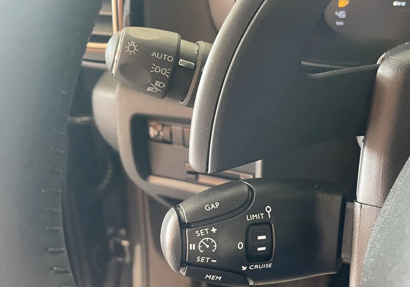 Gros plan sur la commande de régulateur de vitesse au volant d’un Citroën C5 Aircross hybride gris platinium, intérieur noir.
