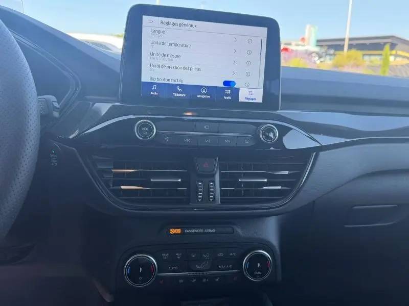 Vue intérieure centrée sur la console centrale du Ford Kuga gris Solar Métallisée avec écran tactile et commandes climatisation.