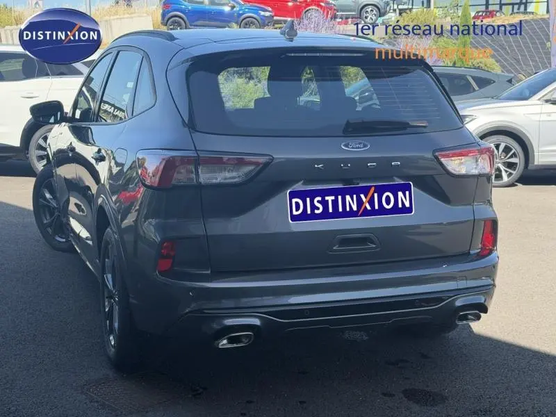 Vue 3/4 arrière droite d’un Ford Kuga gris Solar métallisé avec double sortie d’échappement et feux arrière LED.