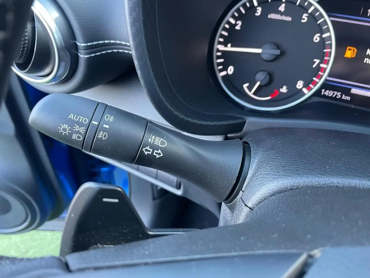 Gros plan sur la manette des feux et clignotants côté gauche du tableau de bord bleu magnetic du Nissan Juke 2024.