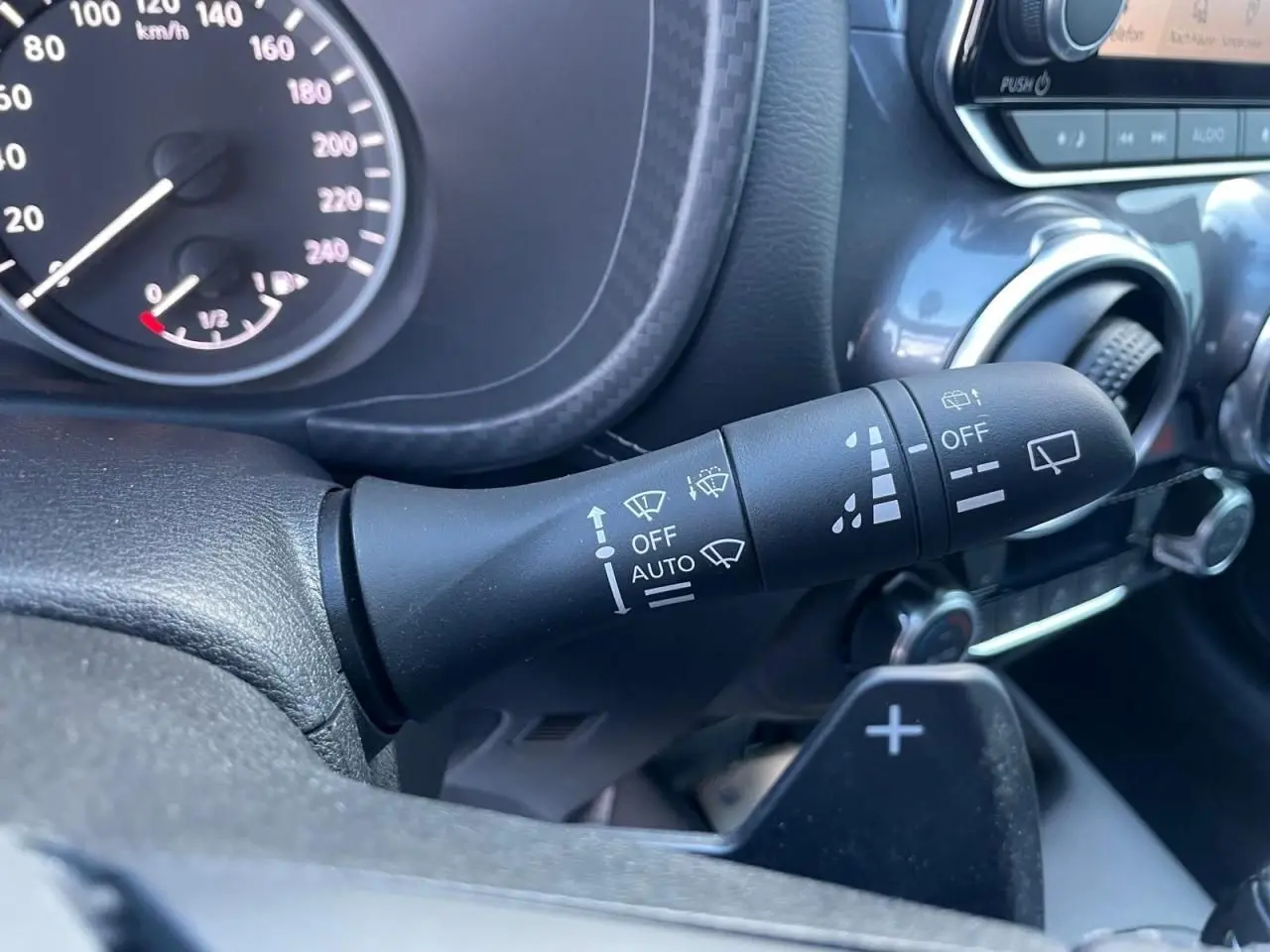 Gros plan sur la commande d'essuie-glace à gauche du volant dans l'habitacle noir du Nissan Juke II 2024.