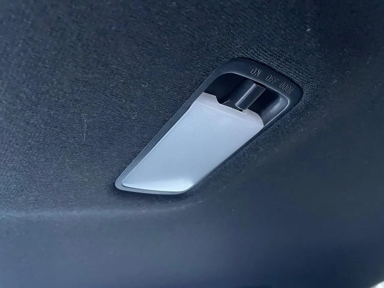 Plafonnier intérieur blanc sur ciel de toit noir du Nissan Juke II bleu magnetic 2024.