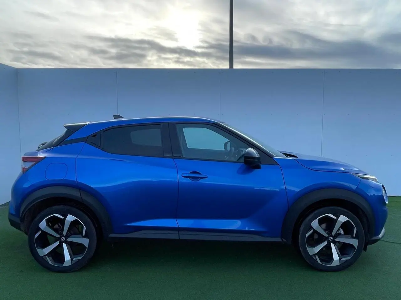Profil droit du Nissan Juke II 2024 en bleu magnetic avec jantes alliage noires et vitres teintées.