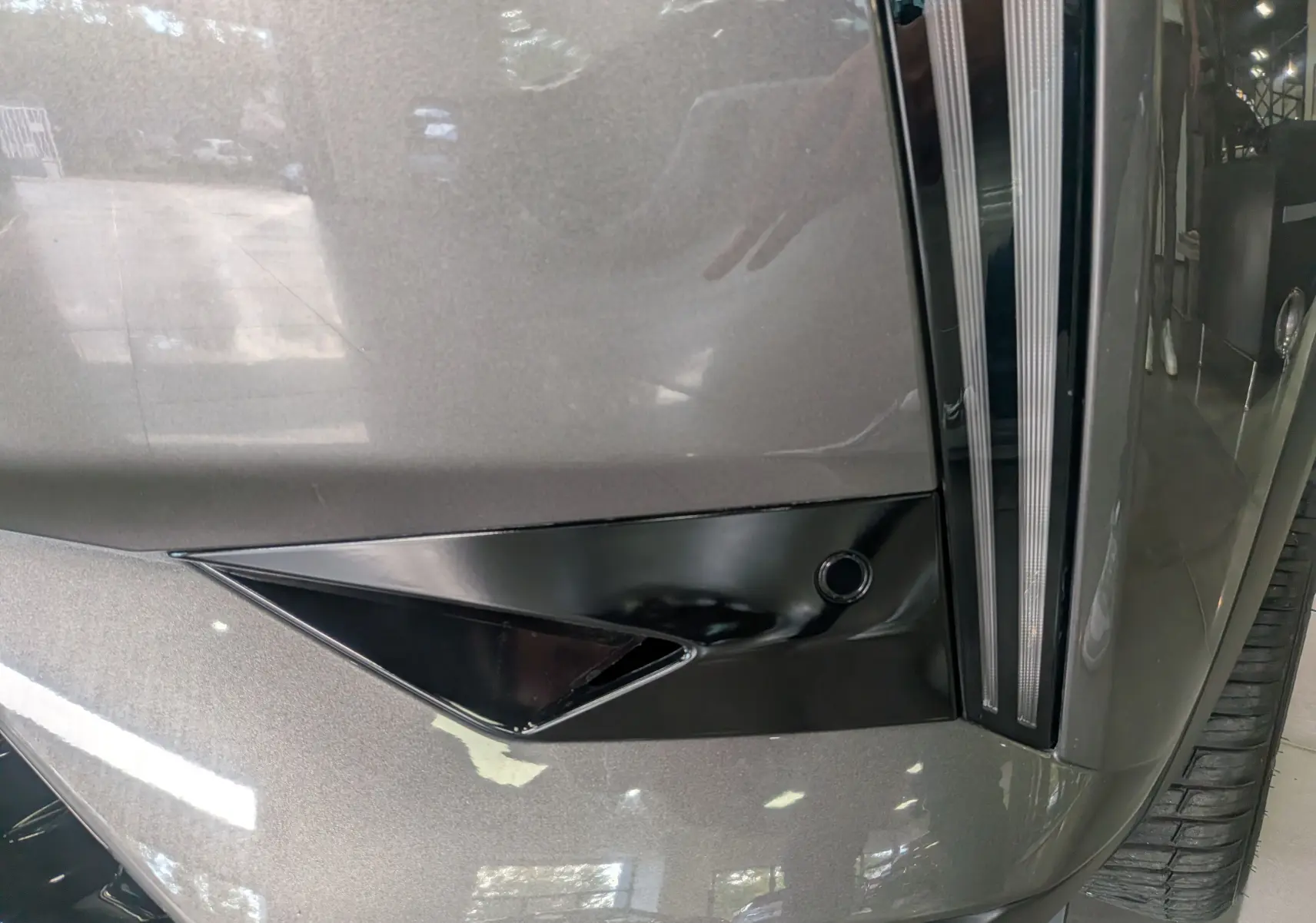 Détail du pare-chocs avant gris Platinium d'une DS3 2024 avec insert noir brillant et capteur de stationnement.