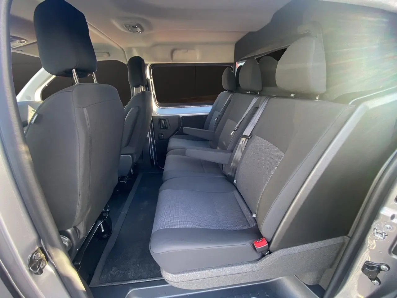 Vue latérale droite de l'habitacle du Citroën Jumpy XL 2025, sièges tissu bi-ton noir-gris avec accoudoirs.