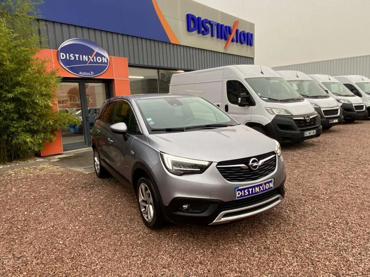 Opel Crossland X gris métallisé en 3/4 avant droit, garé devant un concessionnaire Distinxion.
