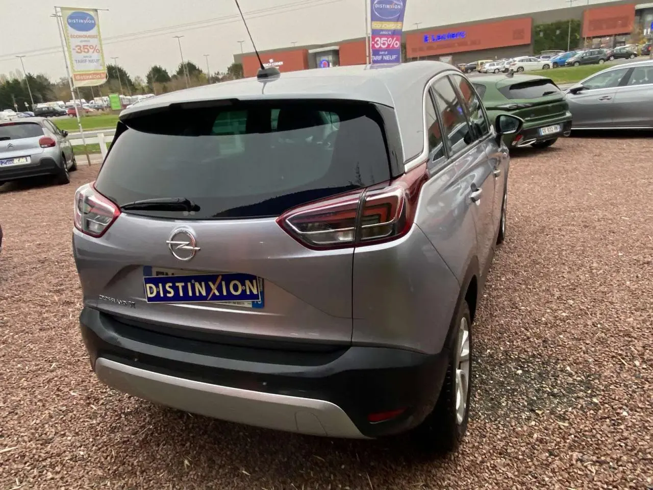 Vue 3/4 arrière droite d'un Opel Crossland X gris métallisé avec vitres surteintées et jantes alliage 16 pouces.