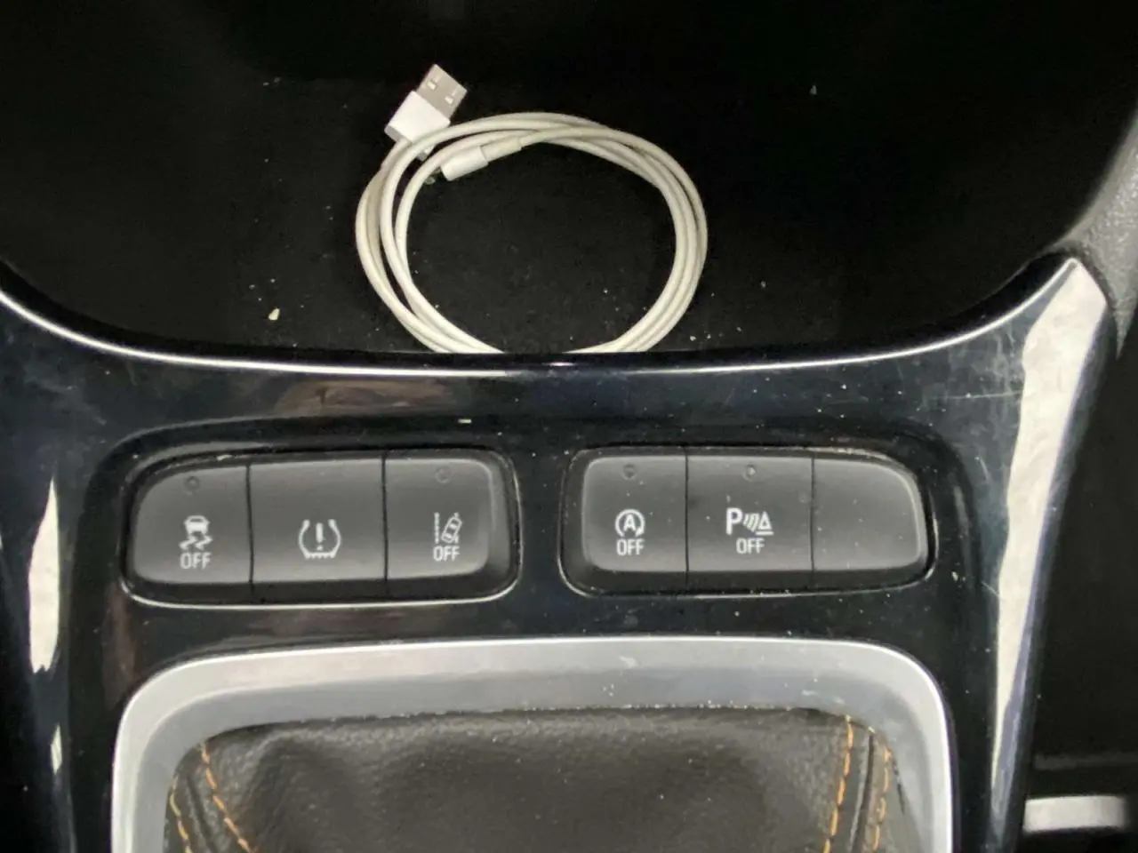 Vue rapprochée du tableau de bord central de l'Opel Crossland X 2020, montrant les boutons de contrôle et un câble USB blanc.
