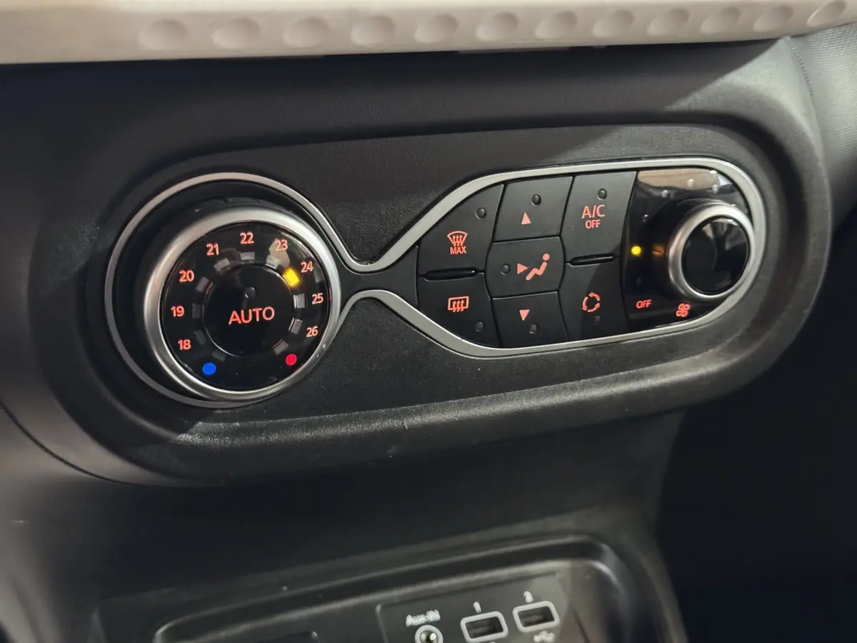 Gros plan sur la commande de climatisation noire avec réglage automatique et boutons lumineux dans une Renault Twingo blanche 2022.