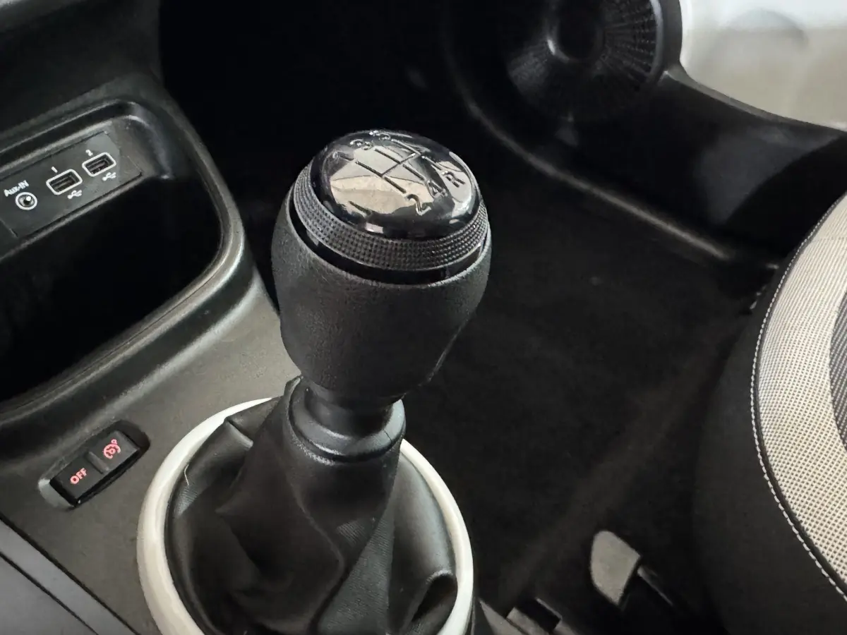 Le levier de vitesses manuel noir de la Renault Twingo blanc, avec ports USB et partie du siège conducteur visible.