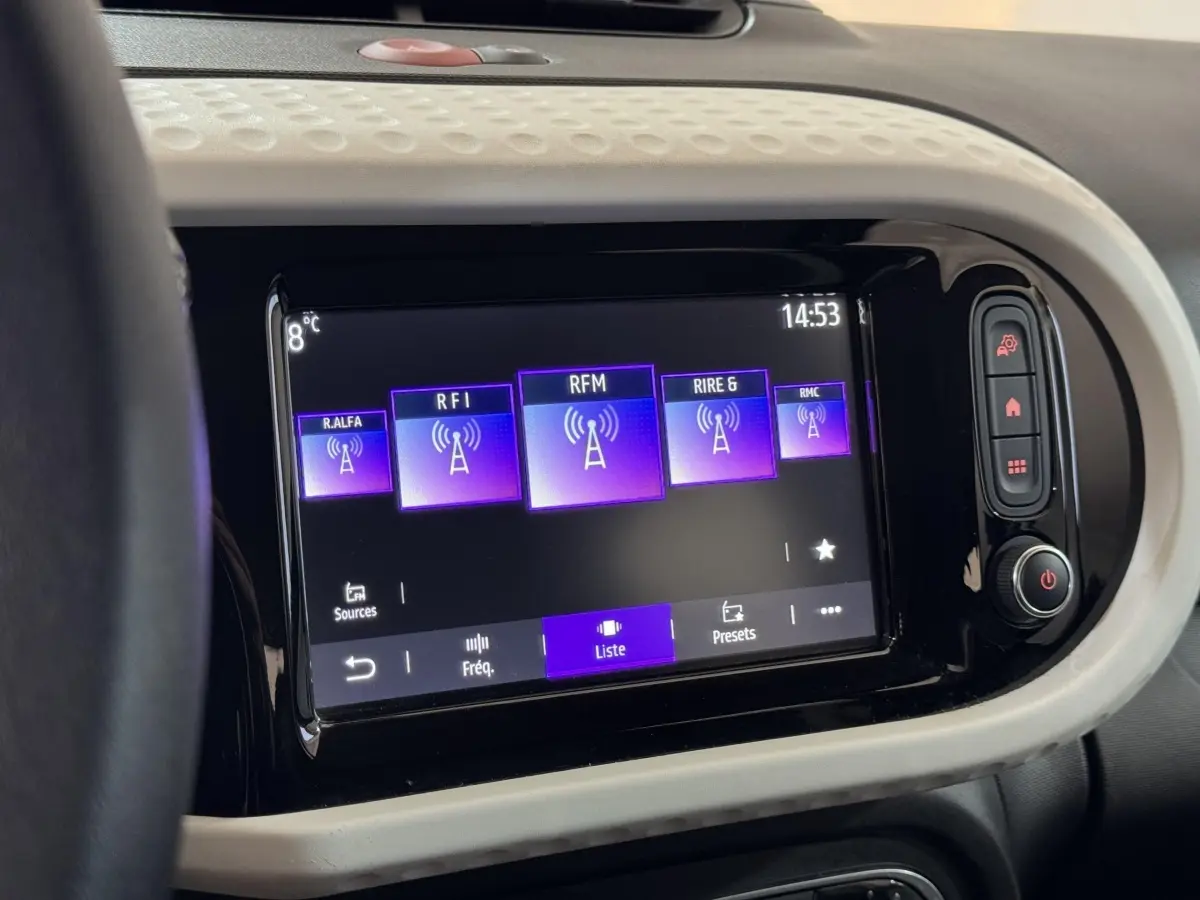 Écran tactile central de la Renault Twingo blanc 2022 affichant les stations radio avec commandes latérales.