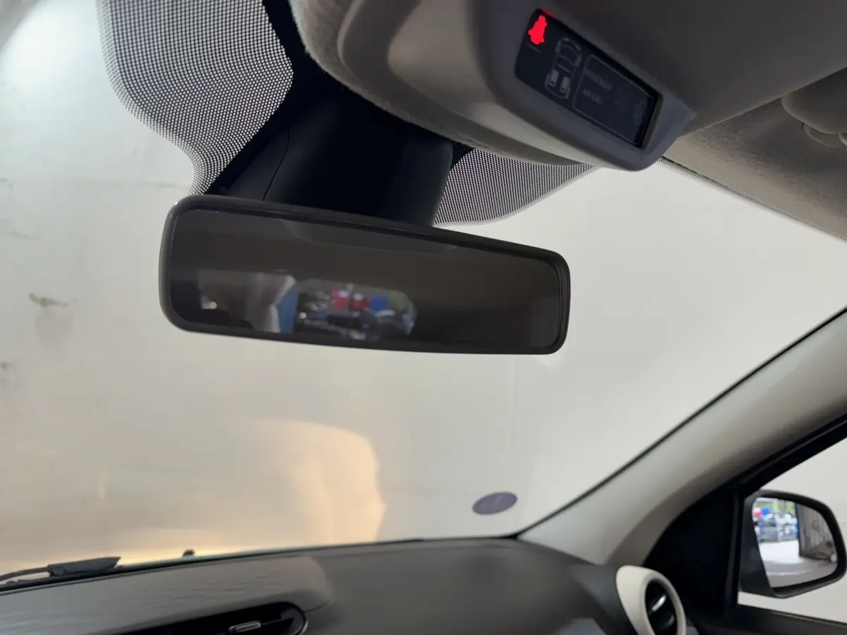 Vue intérieure du rétroviseur central d'une Renault Twingo blanche 2022, avec tableau de bord noir et rétro extérieur visible.