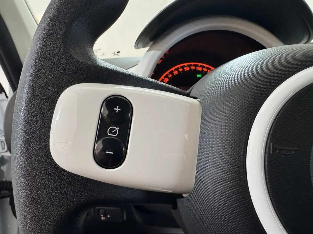 Gros plan sur les commandes blanches du régulateur de vitesse au volant d'une Renault Twingo blanche 2022.