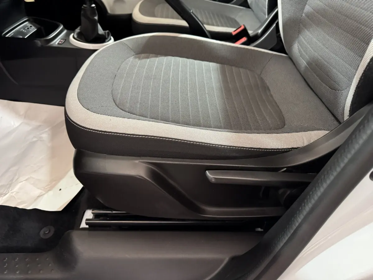 Gros plan sur le siège avant droit gris clair et foncé de la Renault Twingo Equilibre blanche, avec levier de réglage manuel visible.