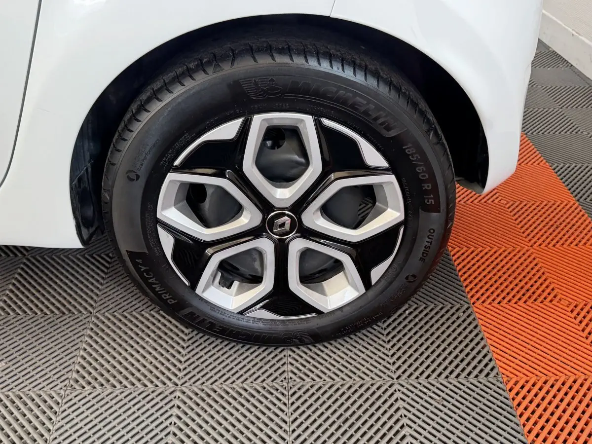 Gros plan sur la roue avant droite blanche d'une Renault Twingo 2022 avec jante noire et argentée au design hexagonal.