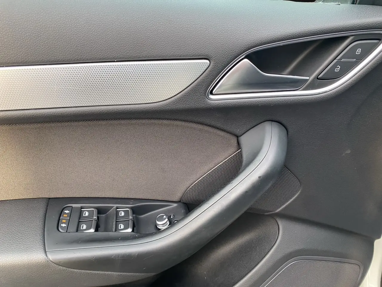 Détail de la porte avant gauche noire avec commandes de vitres et verrouillage sur Audi Q3 blanc 2014.