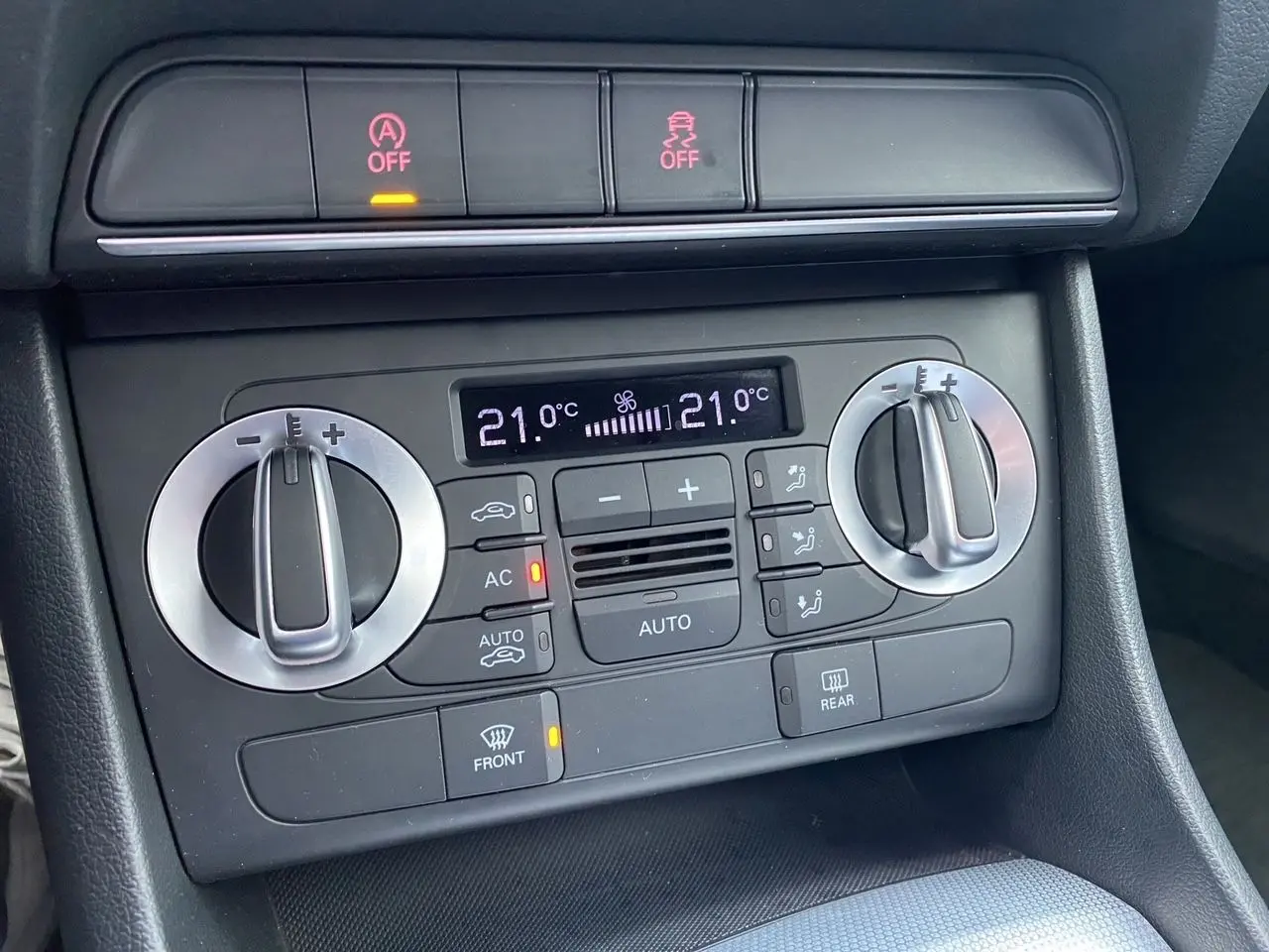Gros plan sur la console de climatisation automatique de l'Audi Q3 blanche, avec affichage digital et commandes rotatives.